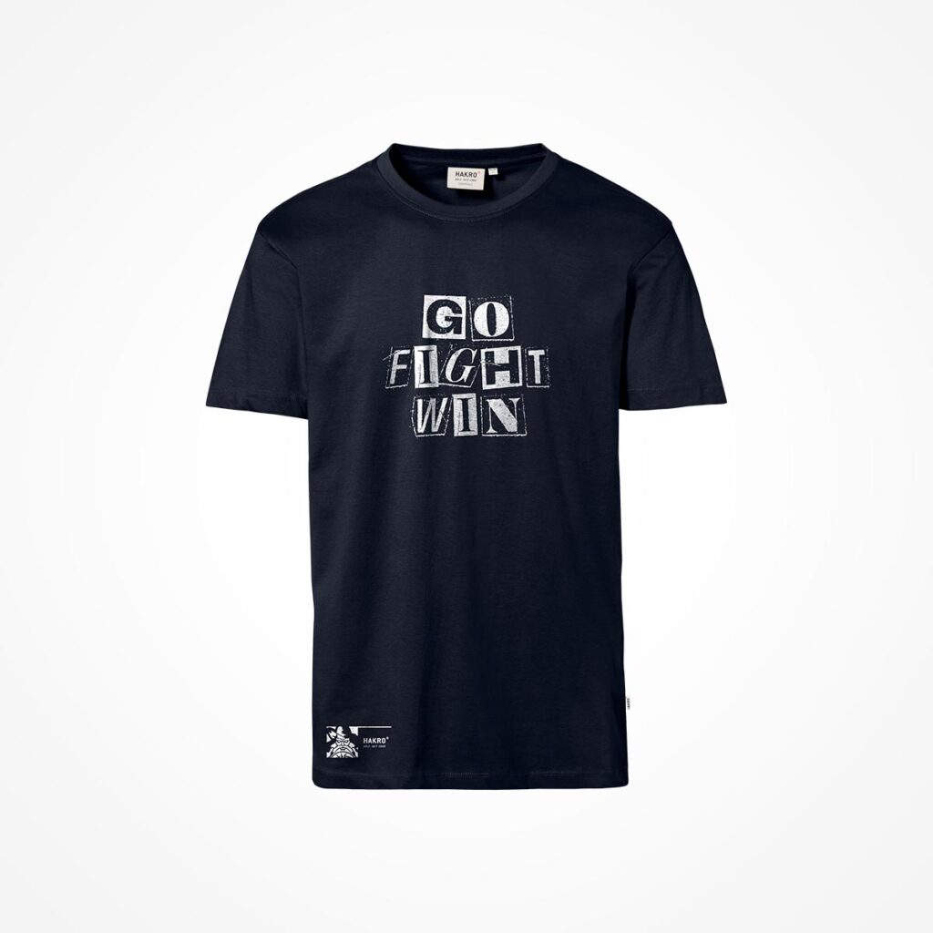 Schwarzes T-Shirt mit der Aufschrift „GO FIGHT WIN“ in weißen, fetten Großbuchstaben auf der Vorderseite. Außerdem befindet sich unten links am Saum eine kleine weiße Grafik und ein Text. Der Hintergrund ist einfarbig weiß.